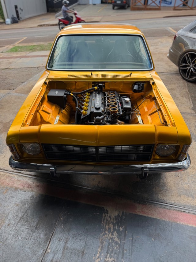 Chevrolet Opala amarelo com cofre aberto e motor 6 cilindros preparado