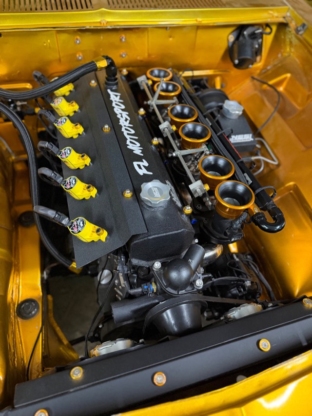 Cofre amarelo com motor 6 cilindros, tampa de válvulas FL Motorsport e corpos de injeção individuais